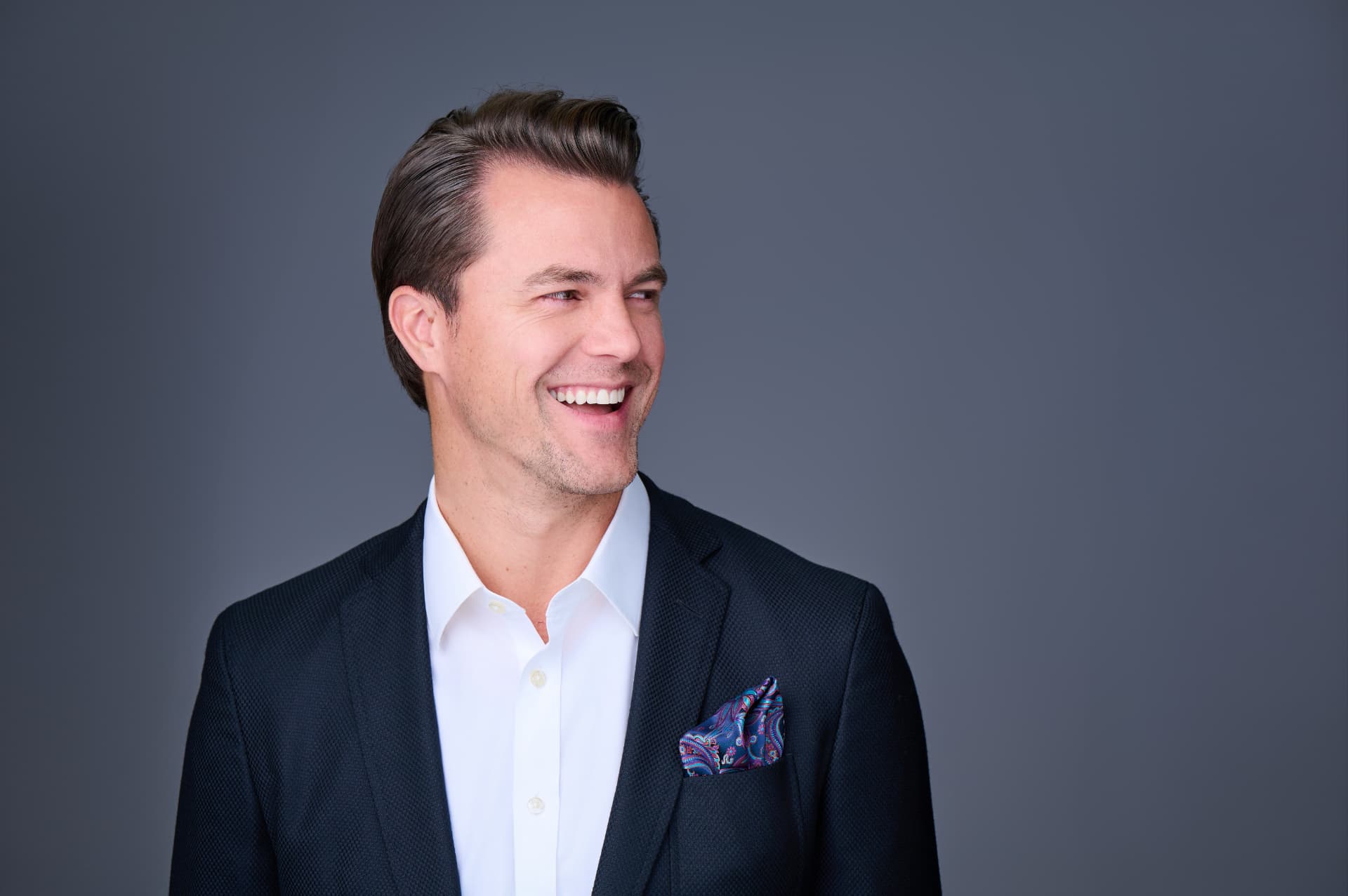 Laughing man in a navy blazer turning to his side during a personal branding session